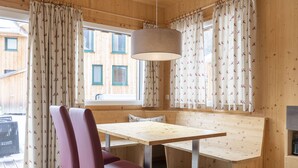 A wooden interior with a bench, two chairs, a table, and a hanging light fixture.