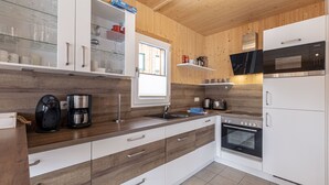 A modern kitchen with wooden cabinets, a built-in oven, a microwave, and a coffee maker.