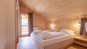 Una habitación de madera con una cama, una ventana y una puerta.