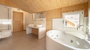 Un baño moderno con techo de madera, una bañera grande, un lavamanos y un espejo.