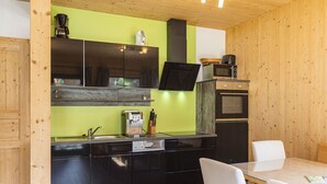 Una cocina compacta con armarios negros, una pared verde y un techo de madera.