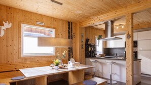 A wooden interior with a dining table, benches, a kitchen area, and a sign reading "STAMMITSCHOR". - Chalet # 65a mit 4 Schlafzimmer, IR-Sauna & Whirlpool (St. Georgen am Kreischberg)
