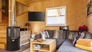 A wooden interior with a sofa, a TV, a fireplace, and a staircase. - Chalet # 65a mit 4 Schlafzimmer, IR-Sauna & Whirlpool (St. Georgen am Kreischberg)