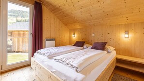 A wooden cabin bedroom with two beds, a sliding glass door to a balcony, and a small heater. - Chalet # 65a mit 4 Schlafzimmer, IR-Sauna & Whirlpool (St. Georgen am Kreischberg)