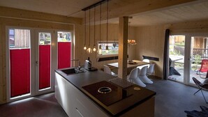 Una cocina moderna con una isla central, puertas correderas rojas y un comedor con sillas blancas.