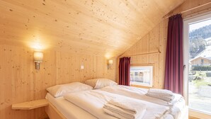 A wooden cabin room with two beds, a window with curtains, and wall-mounted lights. - Chalet # 49b with 4 Bedrooms, IR sauna & whirlpool (St. Georgen am Kreischberg)