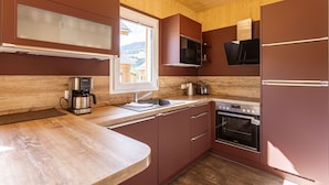 Una cocina funcional con techo de madera, microondas integrado, cafetera y estufa.