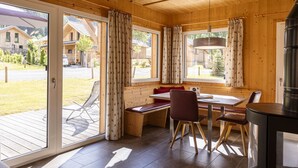 Una cabaña de madera con comedor, un banco y una chimenea.