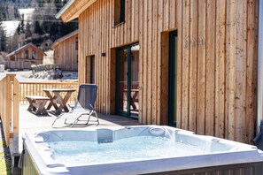 A wooden cabin with a hot tub and outdoor seating.