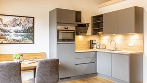 A modern kitchen with grey cabinets, a wooden countertop, and a built-in oven.