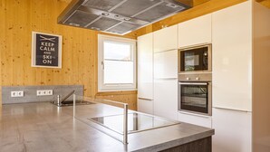 A modern kitchen with white cabinets, stainless steel appliances, and a wooden ceiling.