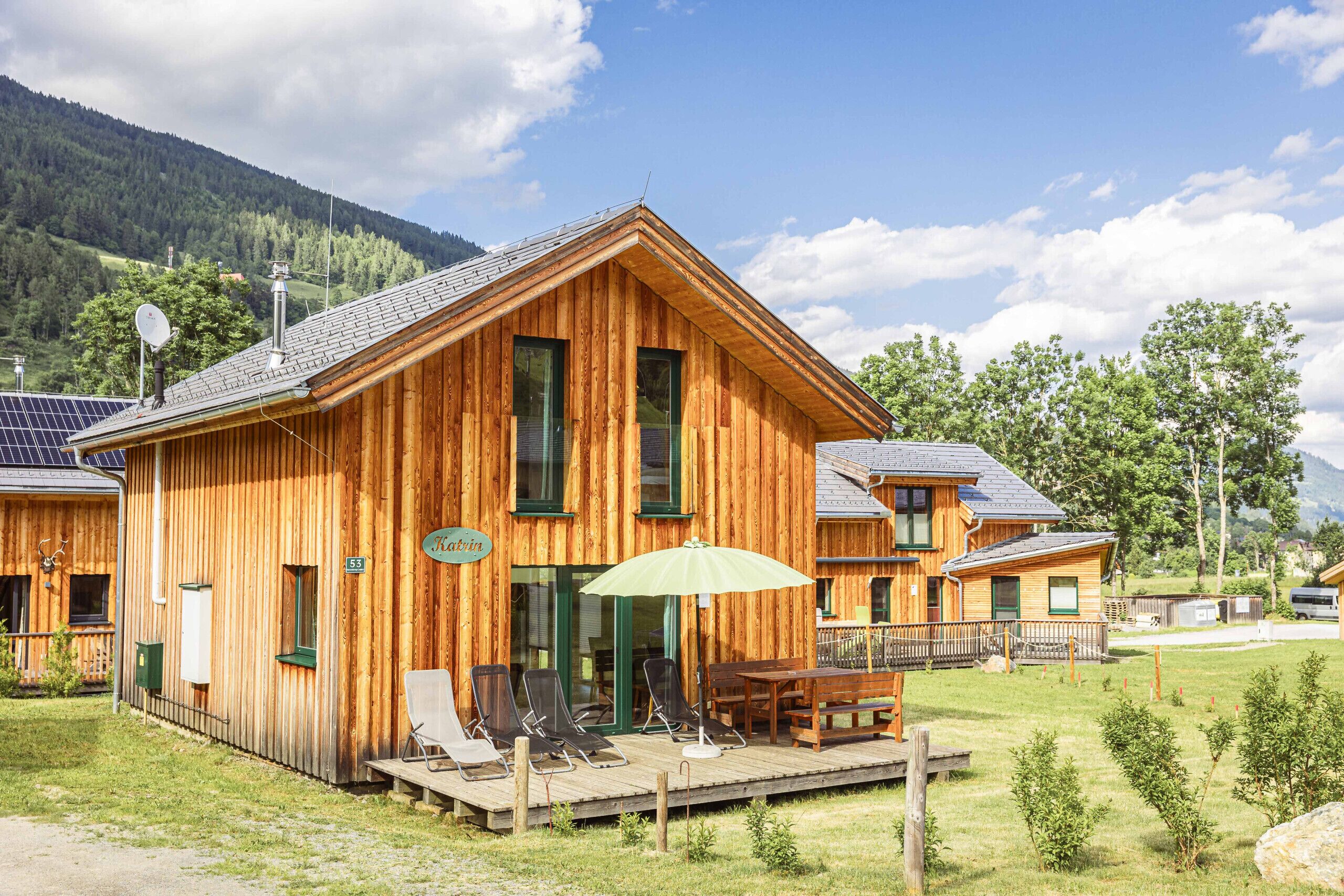 A wooden cabin with a deck, outdoor seating, and a sign indicating the name 'Katrin.'