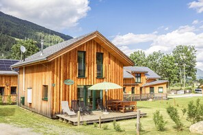 Eine Holzhütte mit einer Terrasse, Sitzgelegenheiten im Freien und einem Schild mit dem Namen 'Katrin'.