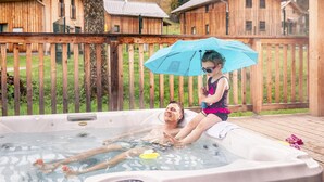 A wooden deck with a hot tub, surrounded by wooden cabins.