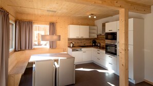 A modern kitchen with white cabinets, a built-in oven, and a dining area with a table and chairs.
