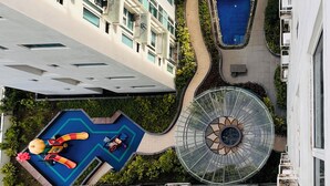 A high-rise building with multiple balconies, a central swimming pool, and a circular glass structure. - One Madison Towers (Iloilo)