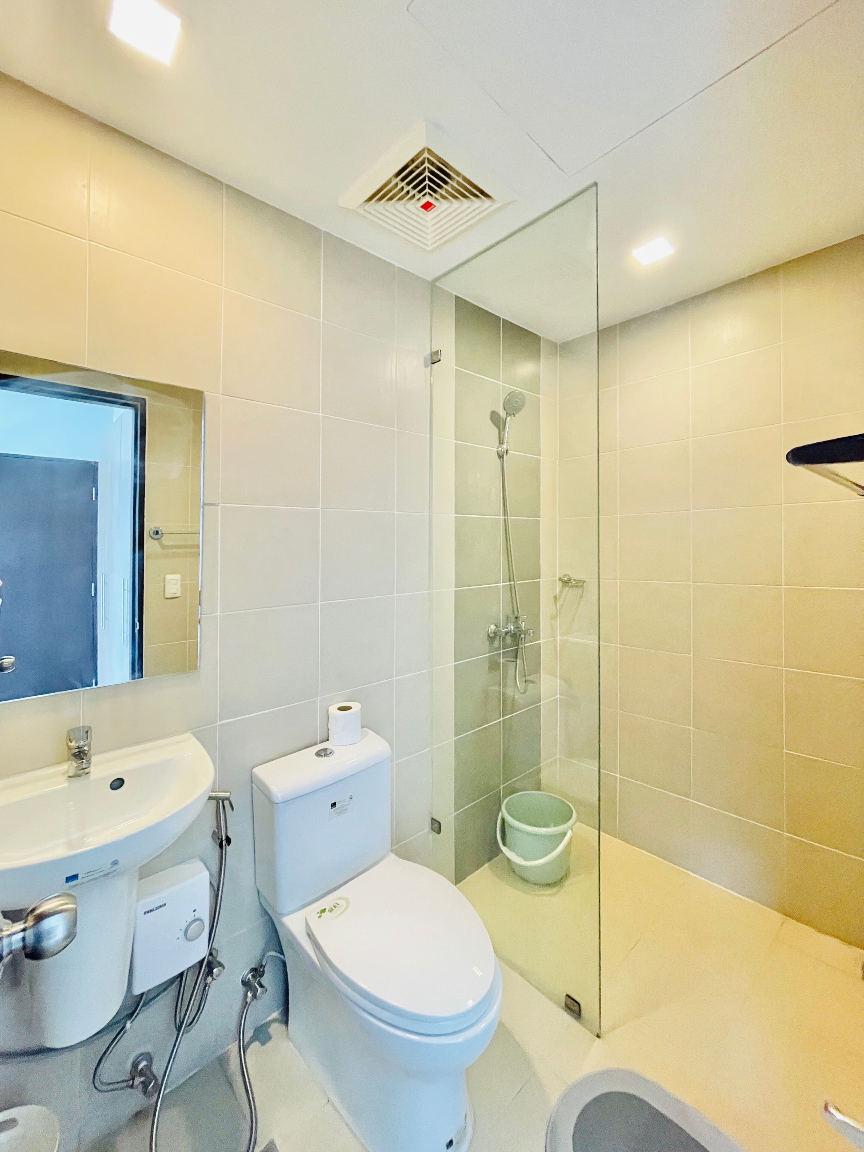 A modern bathroom with a glass-enclosed shower, a white sink, and a toilet.