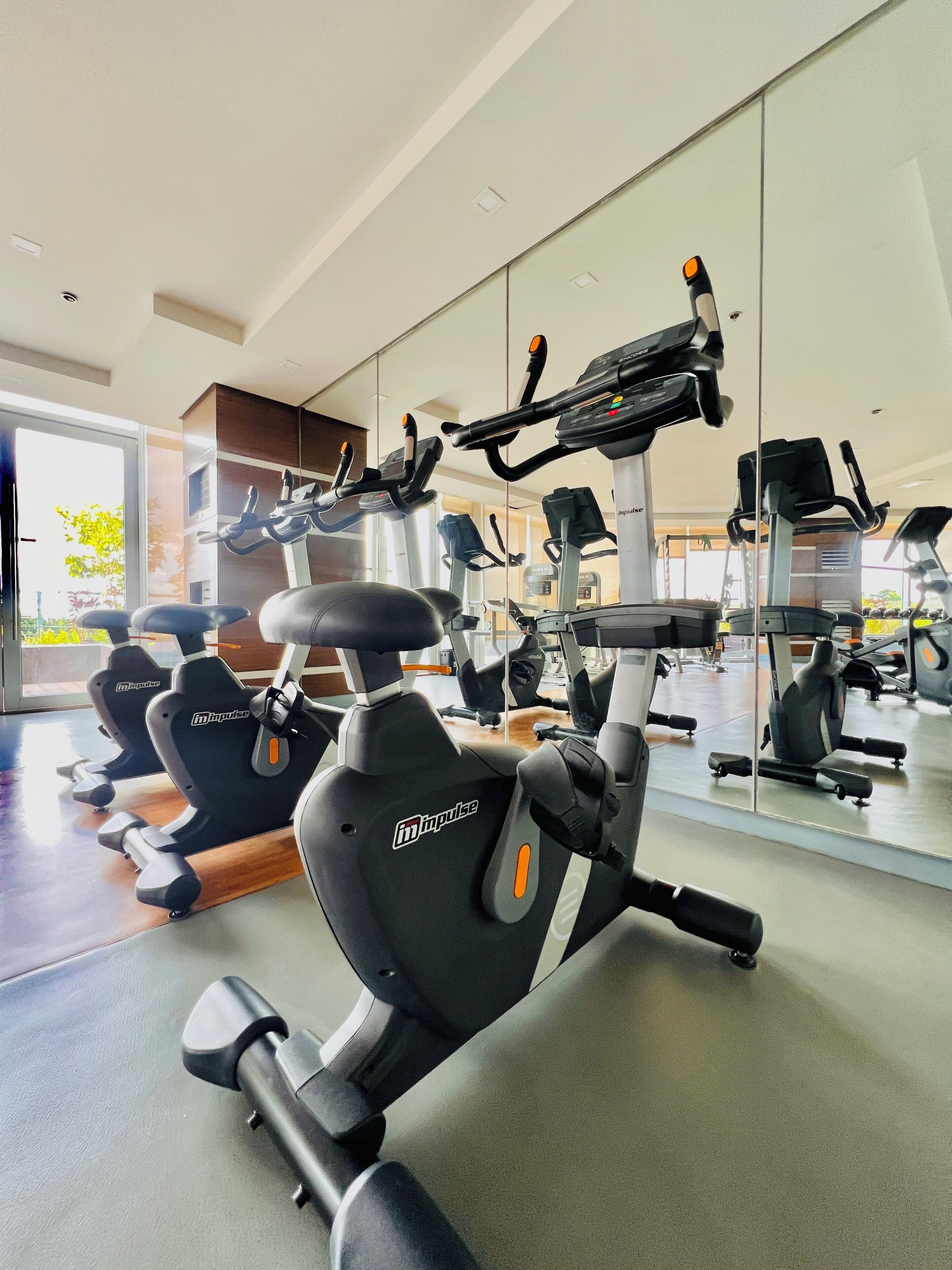 Uma academia com vários equipamentos de exercício, incluindo bicicletas ergométricas e esteiras, dispostos em fileiras.