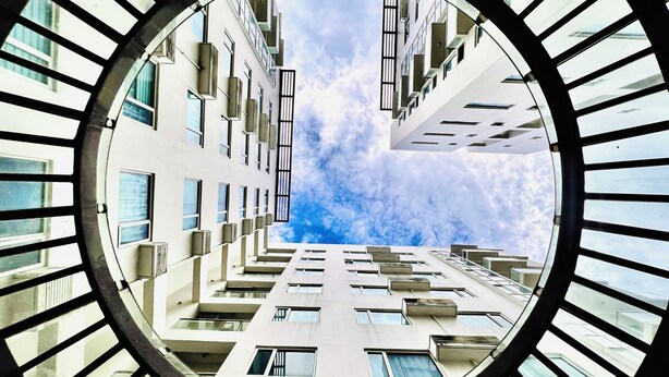 A modern building with a circular window frame, multiple balconies, and a clear sky view. - One Madison Towers (Iloilo)