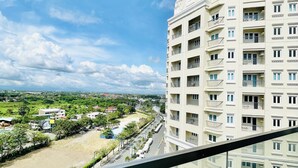 A high-rise building with multiple balconies and a clear view of a road and greenery below. - One Madison Towers (Iloilo)