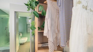 A modern bathroom with a glass shower enclosure, a wooden vanity with a sink, and a plant hanging above the mirror.