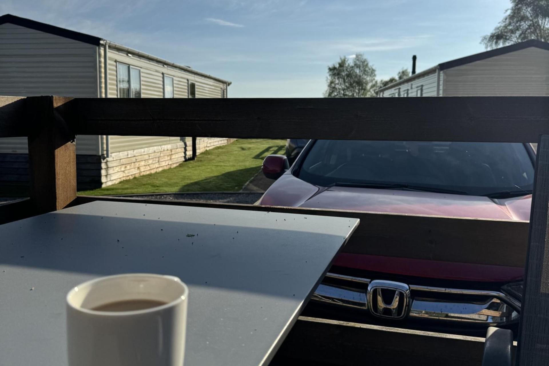 Vista desde el interior de un vehículo, mostrando un coche rojo estacionado frente a casas móviles.