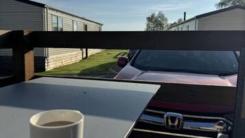 Vista desde el interior de un vehículo, mostrando un coche rojo estacionado frente a casas móviles.