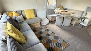A modern living room with a grey sofa, yellow cushions, a patterned rug, and a small table. - Highland Chalet Retreat in Boat of Garten (Boat of Garten)