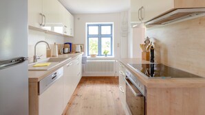 Moderni keittiö, jossa on puukalusteet, sisäänrakennettu uuni ja ikkuna, josta avautuu näkymä vehreään maisemaan.