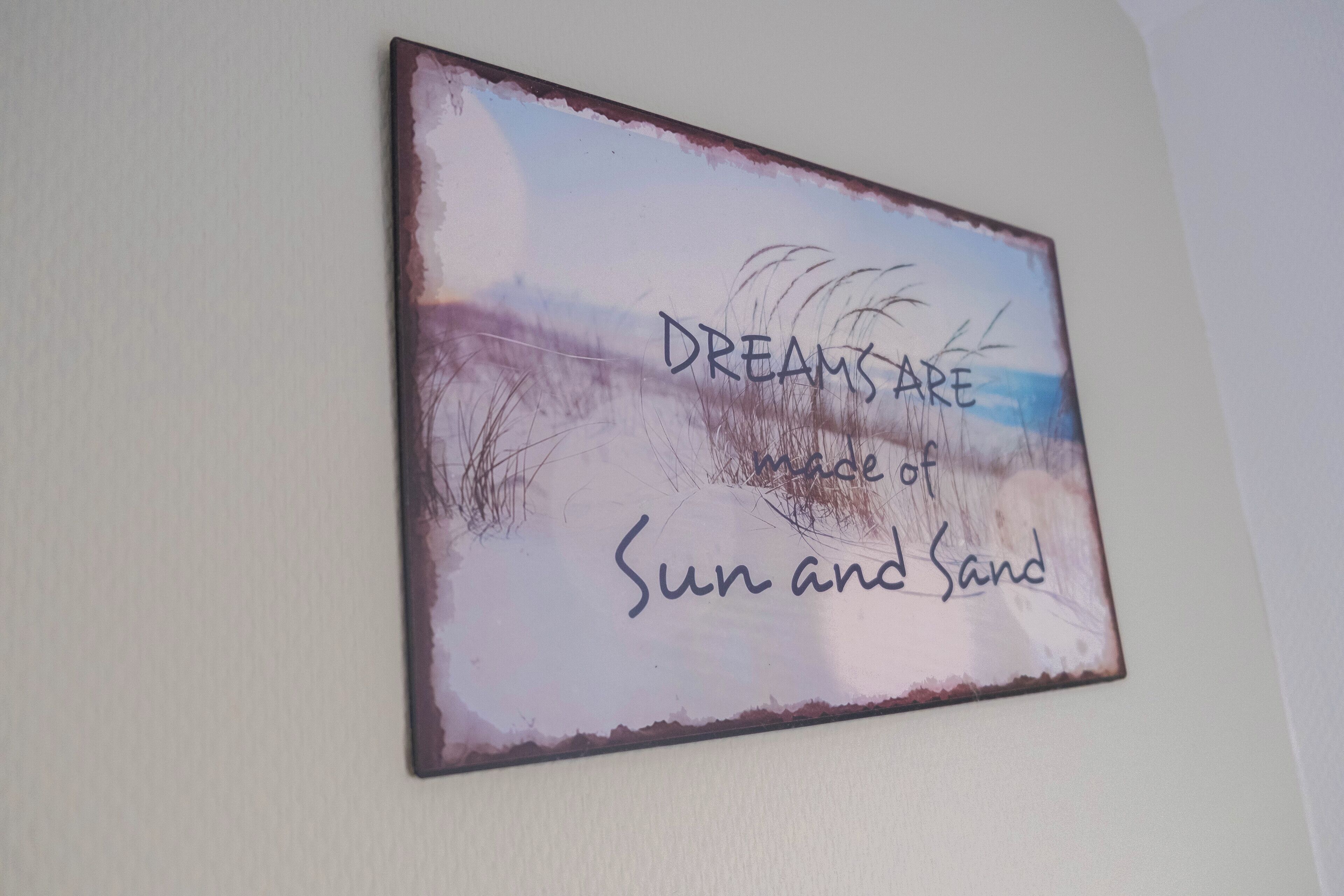 A wall with a painting that reads "DREAMS ARE the essence of Sun and Sand."