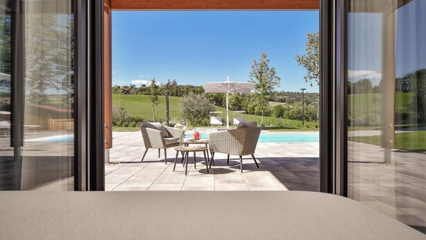 A modern outdoor patio with wicker furniture and a pool. - Tenuta Cà Bassa (Castel San Pietro Terme)