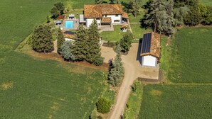 An aerial view of a house with a swimming pool, surrounded by green fields and trees. - Tenuta Cà Bassa (Castel San Pietro Terme)