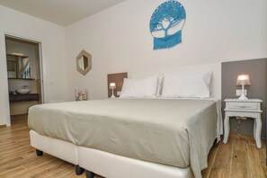 A bedroom with a bed, bedside lamps, a wall mirror, and a decorative tree artwork. - Tenuta Cà Bassa (Castel San Pietro Terme)