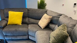 A sectional sofa with multiple cushions in a living room with a patterned rug.