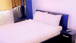A bedroom with a bed, a nightstand, a lamp, and a painting on the wall.