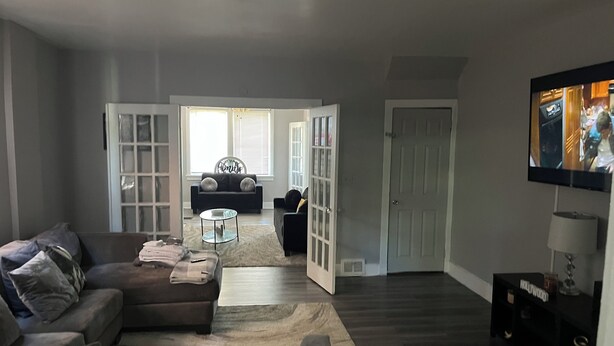 A living room with a sectional sofa, a coffee table, and a TV mounted on the wall. - Charming 3-bedroom house with AC and WiFi in lovely Pittsburgh (Pittsburgh)