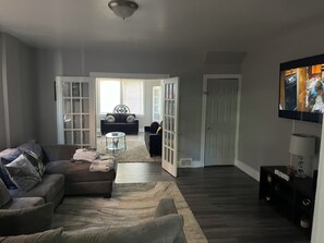 Una sala de estar con un sofá modular, una mesa de centro y un televisor montado en la pared.