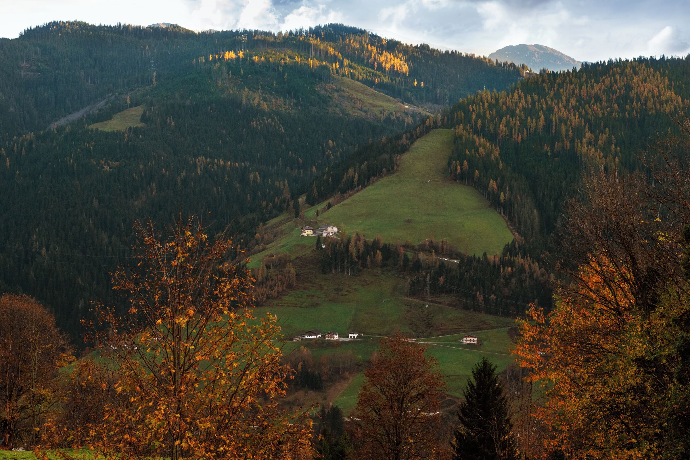 A valley with a small settlement, surrounded by forested hills.