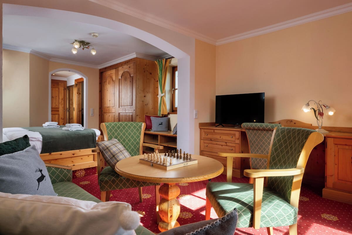 Une pièce confortable avec un lit, une armoire en bois, un téléviseur et une table d’échecs.