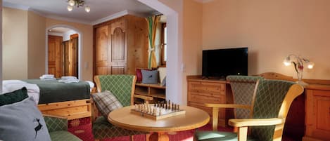 A cozy room with a bed, a wooden cabinet, a television, and a chess table.