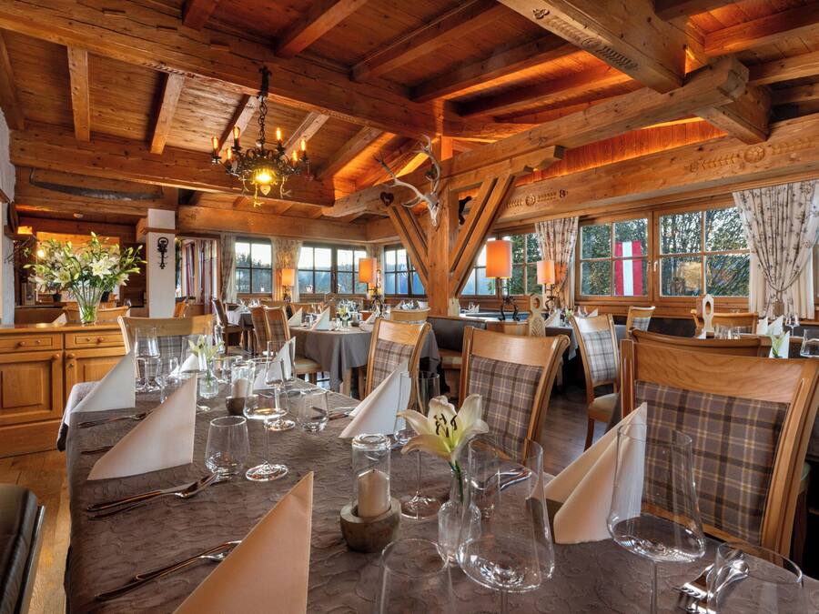 Un restaurante con vigas de madera, ventanas amplias y mesas dispuestas para comer.