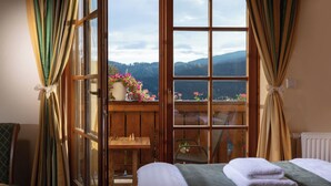 Una habitación con una cama, una mesa de madera y vistas a las montañas a través de un ventanal grande.