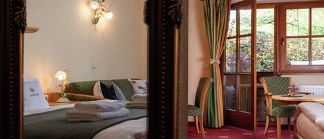 Una habitación de hotel con cama, una silla, una mesa con un vaso y una ventana con cortinas.