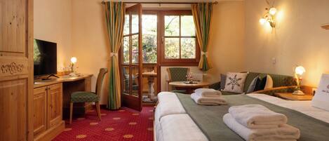 A hotel room with a bed, a desk, a chair, a television, and a window with curtains.