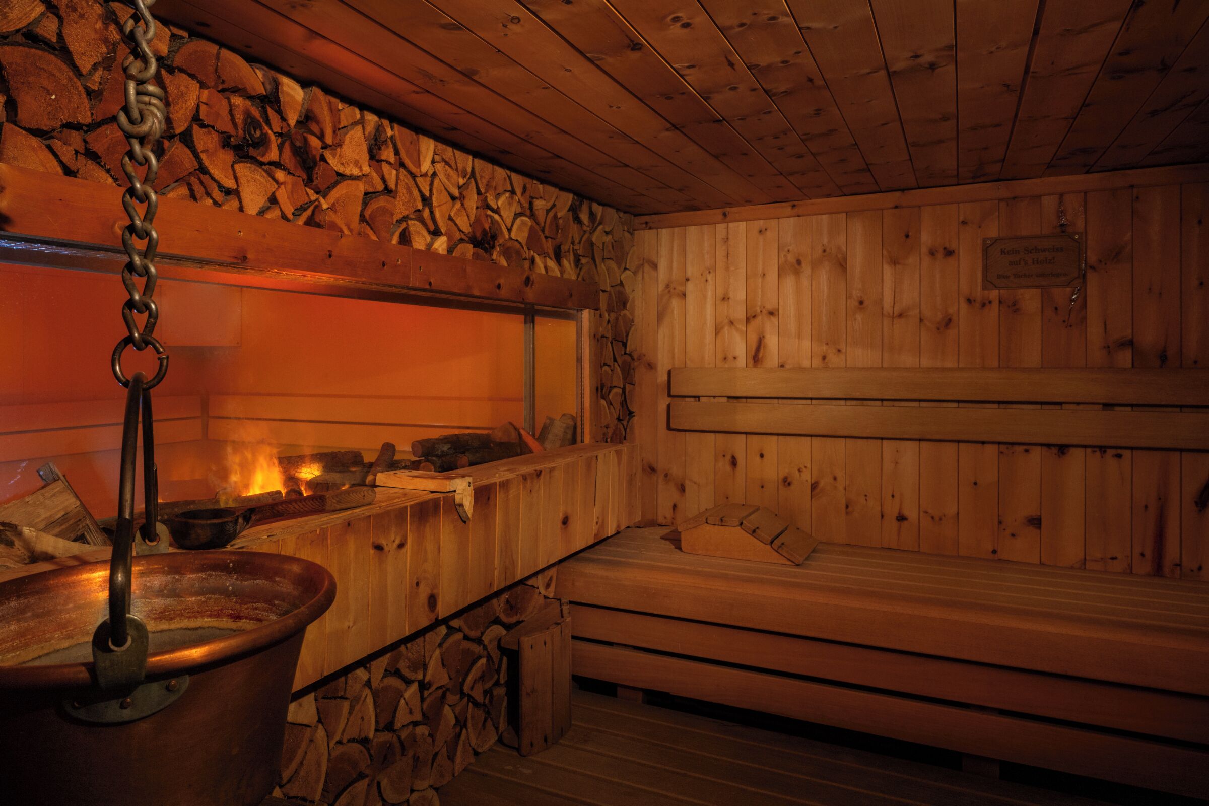 A sauna with wooden benches and a large metal basin.
