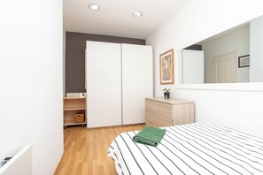 Relax in a serene bedroom with a neatly made bed, dresser, and wardrobe.