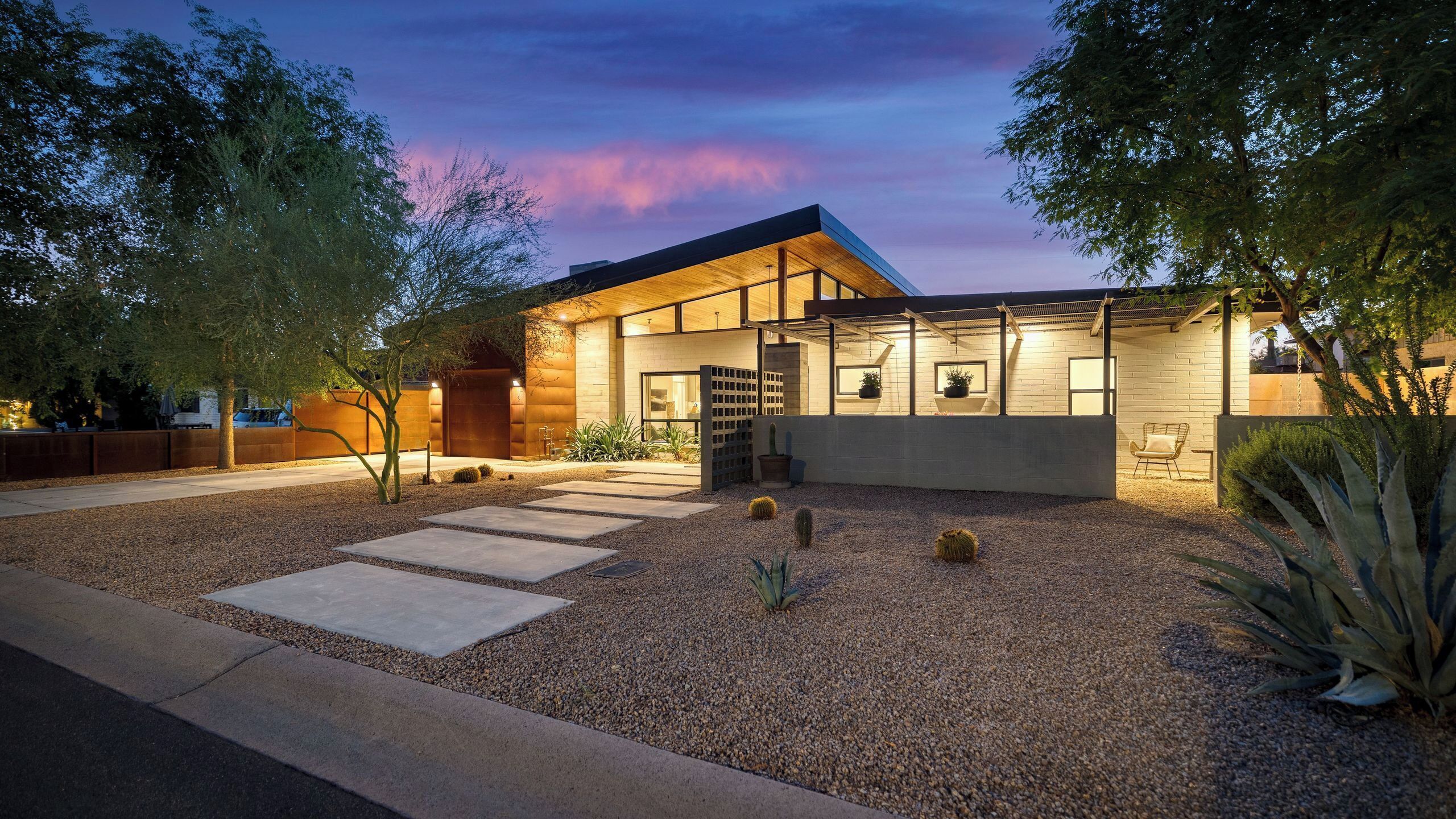 A modern house with a patio, gravel ground, and a wooden fence.