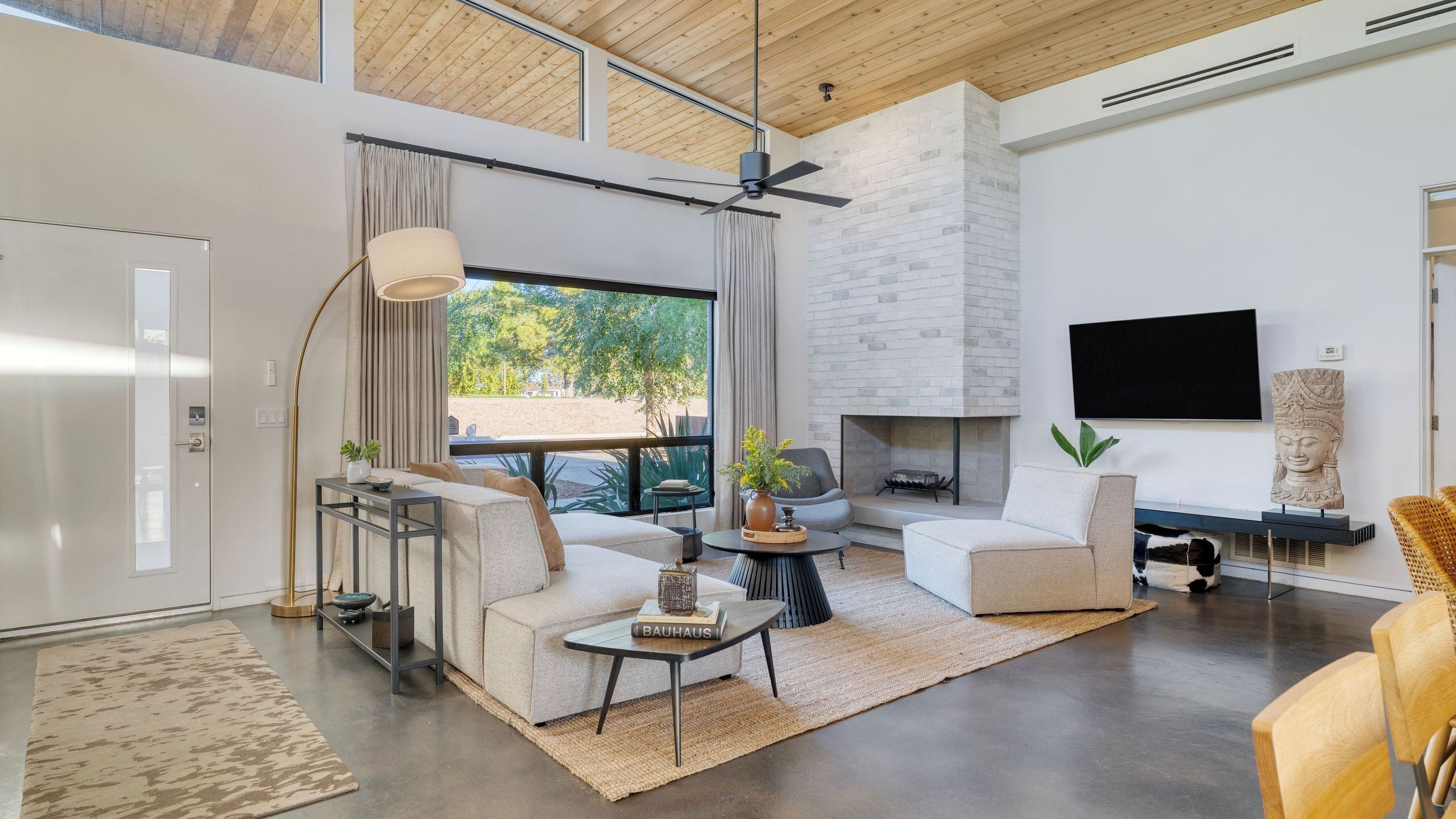 A modern living room with a fireplace, a flat-screen TV, and a large window with curtains.