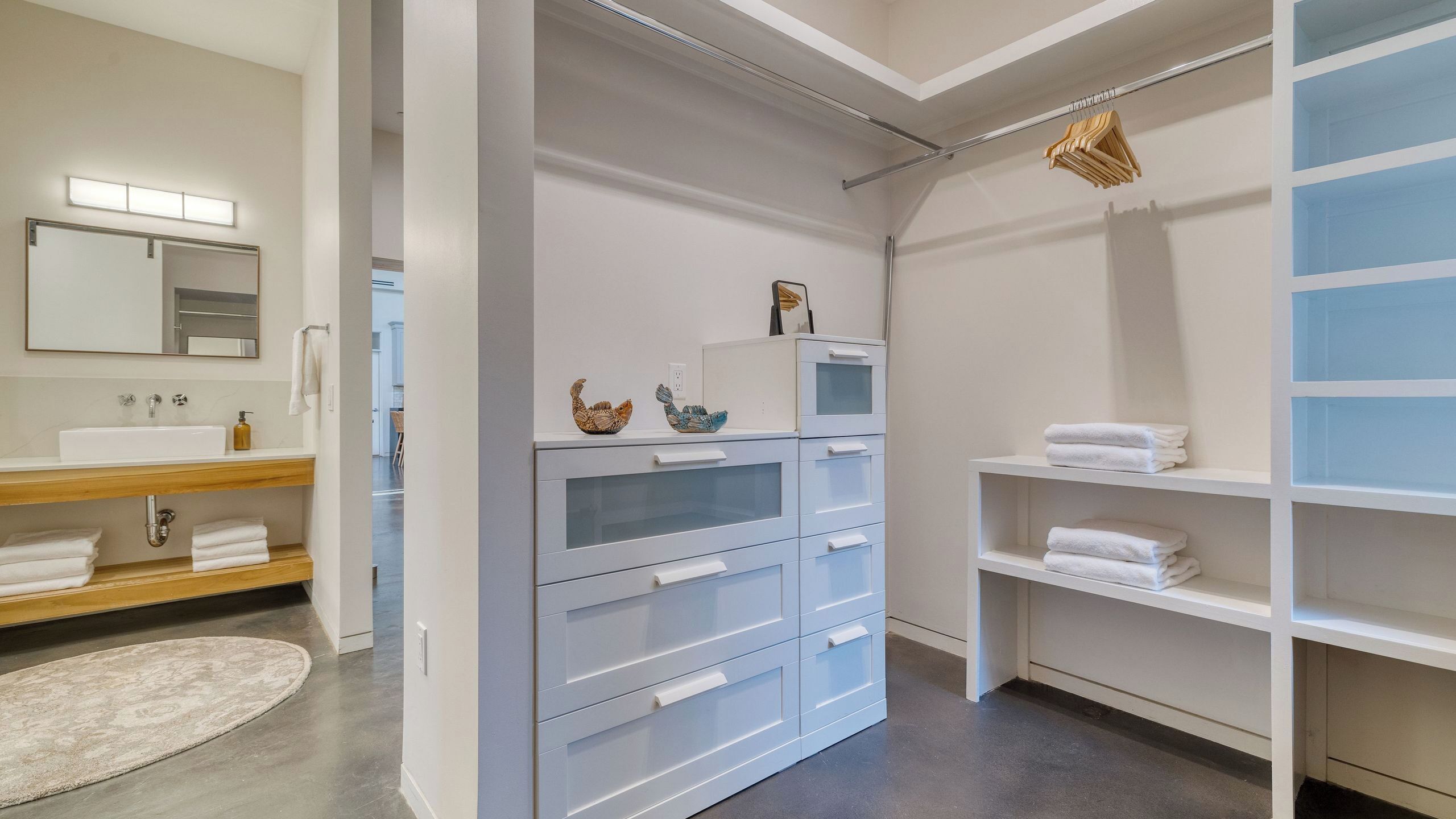 A modern bathroom with a vanity, mirror, and storage shelves.
