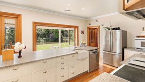 A modern kitchen with a large island, stainless steel appliances, and a view of the garden. - Modernized country house set in beautiful gardens with swimming pool.  
 (Rangitumau)